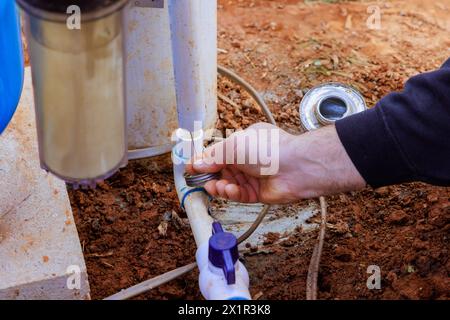 Technician plumber uses clear primer for PVC pipe before gluing it Stock Photo
