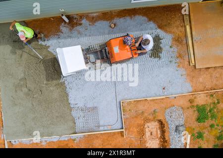 Wet cement is poured into framework during foundation construction using self dumping track concrete buggy Stock Photo