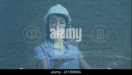 Caucasian female engineer wearing hard hat is holding a digital tablet Stock Photo