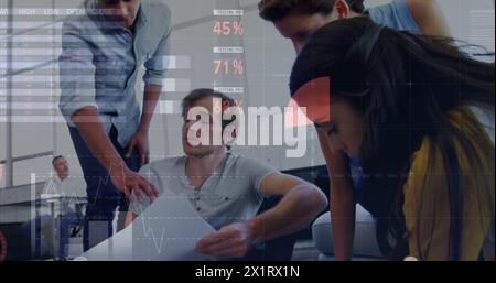 Group of diverse colleagues examining documents, overlay of graphs visible Stock Photo