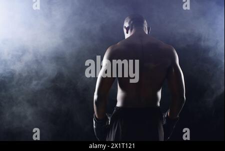 Man, boxer and back of fighter athlete on black background in studio with smoke mist, competition or muscle. Male person, gloves and rear view for Stock Photo