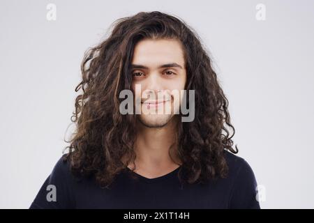 Man, portrait and curly in studio for haircare, style and positive on gray background. Happy male person, face and confident for beauty or cosmetics Stock Photo