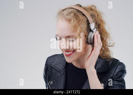 Relax, music or happy woman in headphones in studio for singing or streaming on grey background. Mockup space, face or girl listening to radio Stock Photo