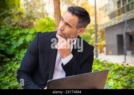 Thoughtful businessman working on his laptop outdoors. Stock Photo