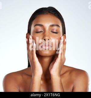 Studio, face and beauty with Indian woman, hands and cosmetic or makeup. Cosmetology, skin or confidence for female model, dermatology and salon or Stock Photo