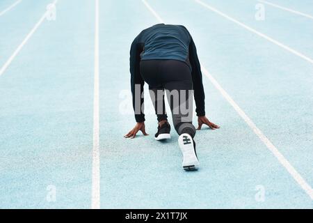 Running, fitness and person on track for race, challenge and competition for field event in stadium. Sports, health and back of runner at start for Stock Photo