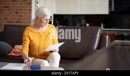 Confident senior woman calculation bills, working with papers at home Stock Photo