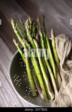 Fresh sprouts of picked asparagus in metal colander on wooden table. Top view. Food photography Stock Photo