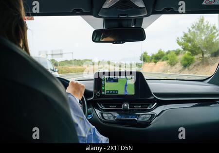 Strasbourg, France - Jun 28, 2023: A female driver uses GPS for navigation the Apple Computers CarPlay interface, the screen showing the way ahead, hands firmly on the wheel. Stock Photo