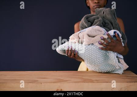 African woman, clean laundry and fresh in home with mockup and charity donation by dark background. Black person, fabric care and natural detergent by Stock Photo
