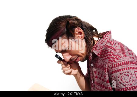 A blind man with modern hairstyle is looking through a magnifying glass. Stock Photo