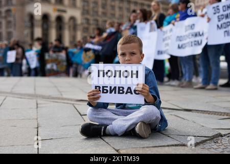 Little Ukrainian boy sitting with a sign 'Captivity Kills' at a peaceful demonstration in Ukraine. Kyiv - 13 April,2024 Stock Photo