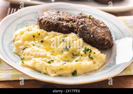 Mashed potatoes topped with melted butter as a side dish to meatballs. Stock Photo