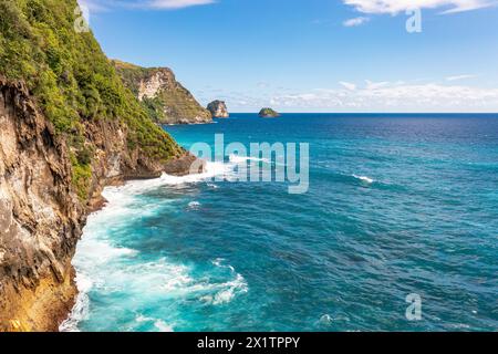 Blue sky over the ocean. White foam of waves breaks against rocks. Klungkung, Bali, Indonesia Stock Photo