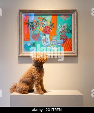 David Messum Fine Arts, London, UK. 18th Apr, 2024. David Messum presents an exhibition of colourful works by French artist, Nancy Delouis who works from a light-filled Limoges studio. Image: Table aux Faiences Bleues, oil pastel on paper, is admired by Poodle Jack. Credit: Malcolm Park/Alamy Live News Stock Photo