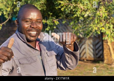 happy african worker with a smile holding thumbs up, outdoors in a sunny day, Stock Photo