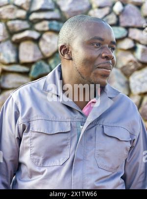 happy african worker with a smile , working outdoors in a sunny day, rock wall background Stock Photo