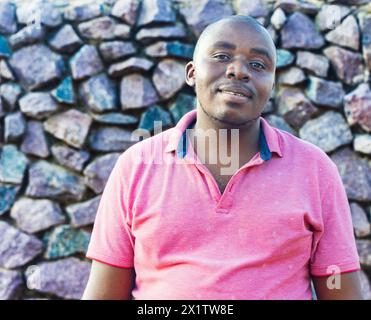 happy african man with a smile , outdoors in a sunny day, rock wall background Stock Photo