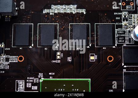 A brown printed circuit board with a processor chip and video memory strips. Electronic components on the graphics card. Stock Photo