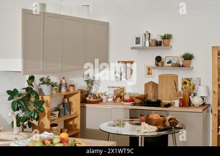 Corner of spacious kitchen of modern apartment with small round glass table standing in the center surrounded by various furniture Stock Photo