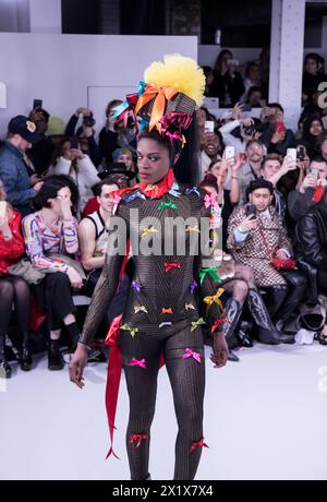 Pam Hogg fashion show during London fashion week black model on a pit catwalk dressed in black onesie colourful bows Stock Photo