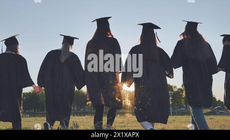 Graduate students walking through an evening meadow at sunset. Stock Photo