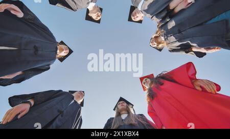 Graduates in robes stand in a circle. View from below. Stock Photo