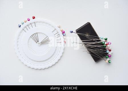 Multicolored pins on a white background. Pins and a sewing magnet. Stock Photo