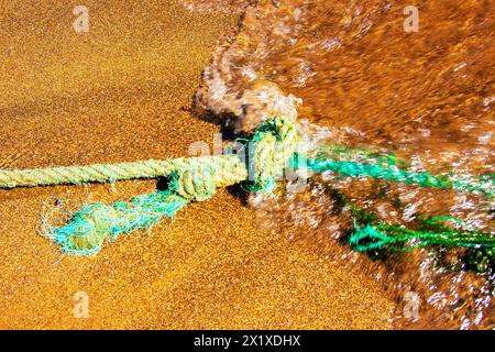 Closeup of an old nautical rope for mooring fishing boats on the Atlantic Ocean in Gran Canaria during an incoming water wave. Rope and knot backgroun Stock Photo