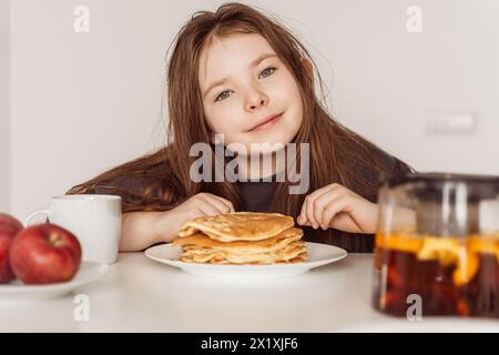 Happy morning. Breakfast of a happy child. Little pre-teen girl with a big stack of pancakes for breakfast. Selected Focus. High quality photo Stock Photo