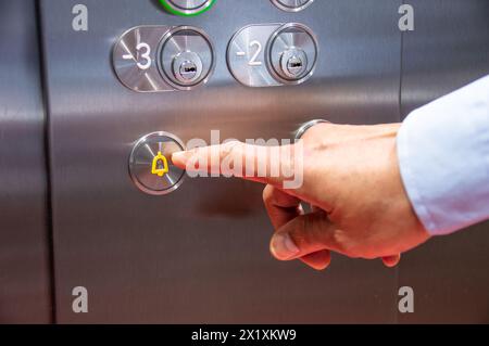 Close-up of hand pressing the alarm button in the elevator Stock Photo