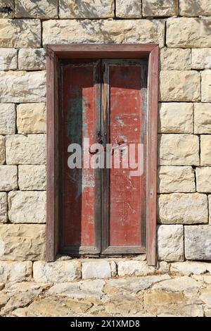 A wooden closed door with peeling red paint. Stock Photo
