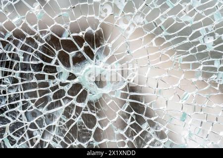 Closeup detail macro view of cracks spreading across a shattered glass panel, single point damage, broken tempered glass, building part, vehicle windo Stock Photo