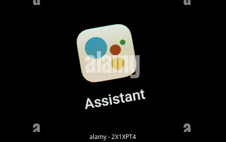 Close-up view of the Google Assistant app logo displayed on a smartphone or mobile device screen, highlighted against a dark background. AI assistants Stock Photo