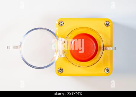 Large red emergency stop button see from above, top view, with open cover, industrial workplace safety, heavy-duty machine stop mechanism, asset on wh Stock Photo
