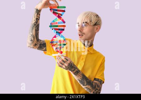 Tattooed young man with DNA model on lilac background Stock Photo