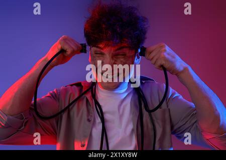 Electrocuted young man with burnt face and plugs on dark background, closeup Stock Photo