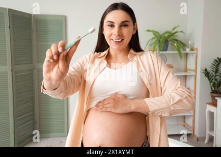 Young pregnant woman with tooth brush in light bathroom Stock Photo