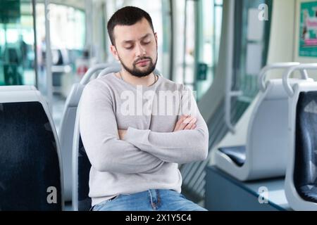 Young bearded guy sleeping on seat in tram Stock Photo