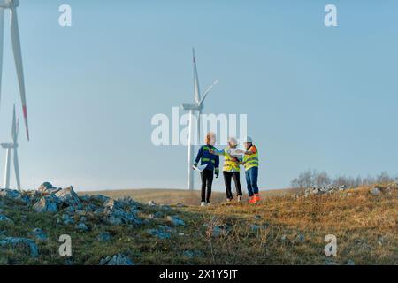 A team of engineers and workers oversees a wind turbine project at a modern wind farm, working together to ensure the efficient generation of Stock Photo