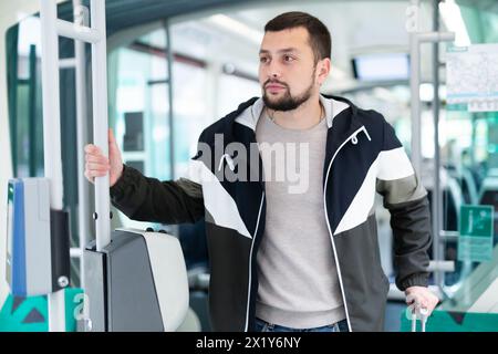 Young bearded man with suitcase riding in streetcar Stock Photo
