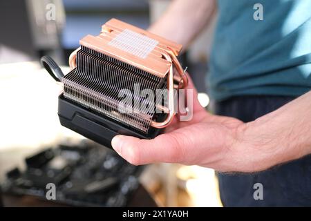 hands of young male master install cooler with copper heat pipes for the processor, other parts of pc into case, the concept of repairing equipment, a Stock Photo