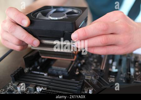 hands of young male master install cooler with copper heat pipes for the processor, other parts of pc into case, the concept of repairing equipment, a Stock Photo