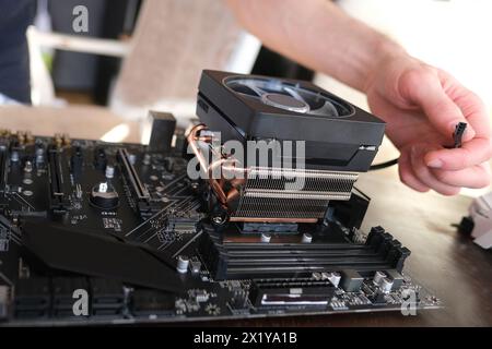 hands of young male master install cooler with copper heat pipes for the processor, other parts of pc into case, the concept of repairing equipment, a Stock Photo