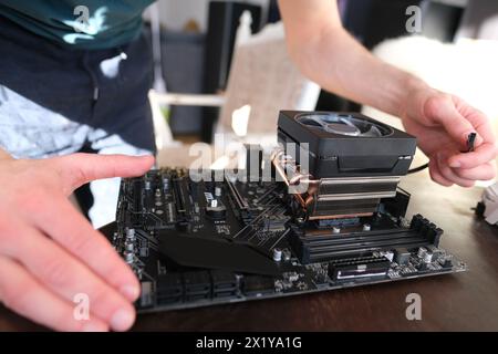 hands of young male master install cooler with copper heat pipes for the processor, other parts of pc into case, the concept of repairing equipment, a Stock Photo