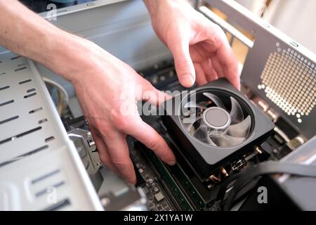 hands of young male master install cooler with copper heat pipes for the processor, other parts of pc into case, the concept of repairing equipment, a Stock Photo