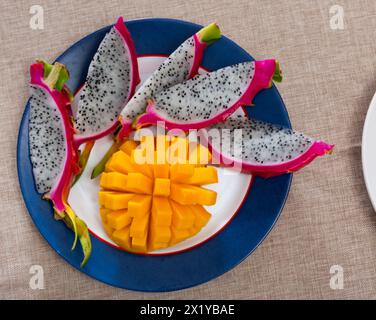 Slices of yellow-orange mango and pink pitaya on plate Stock Photo