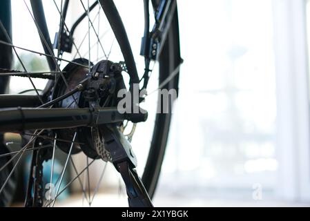 Close-up view of the rear wheel of an E-bike, featuring the brake disc and kickstand joint. Bright background on the right suitable for text. Stock Photo