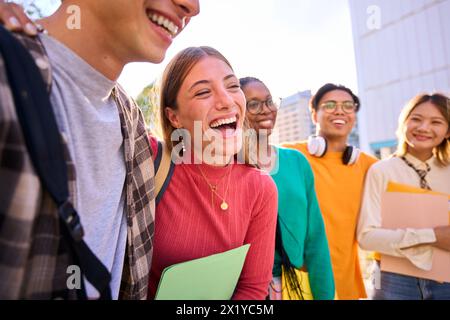 Laughing Caucasian female student with multiracial group of classmates posing hugging  Stock Photo
