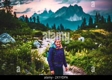 Description: Smiling woman enjoys evening with impressive view on on Cadini di Misurina in the evening. Lake Sorapis, Dolomites, Belluno, Italy, Europ Stock Photo
